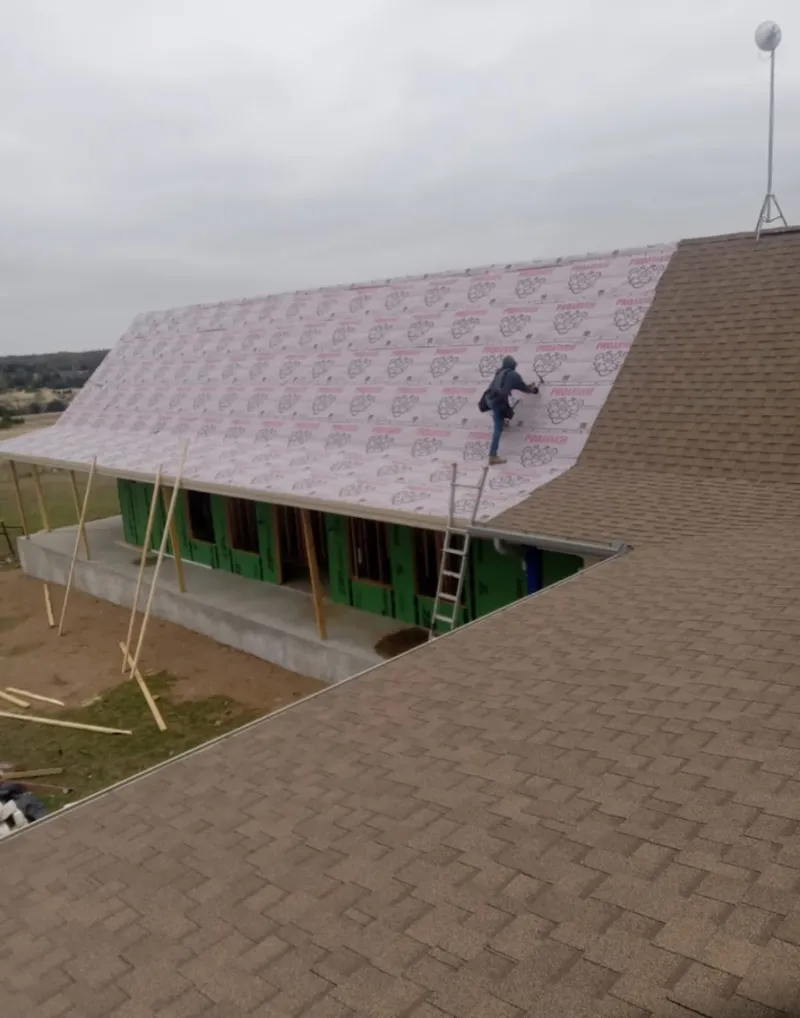 Worker preparing underlayment for a metal roof installation in Eunice